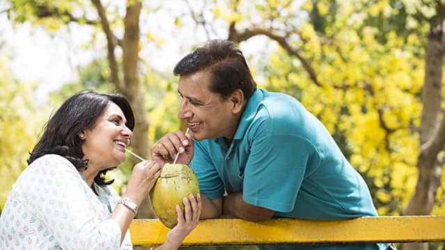 older couple smiling drinking from a coconut