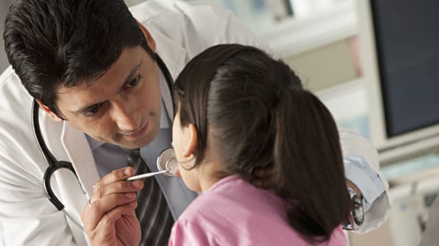 a dentist holding a mouth mirror examining a girl teeth
