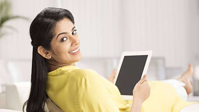 a woman smiling while sitting down holding a tablet