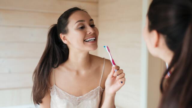 Young Girl Brushing Teeth In Front Of Mirror