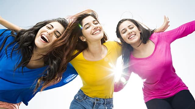 three women smiling brightly while spreading their arm around each other