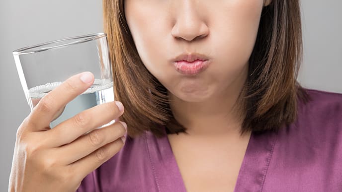 Woman rinsing and gargling while using mouthwash from a glass