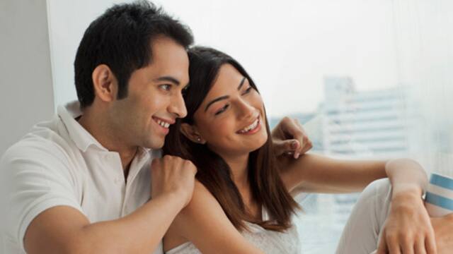 a man and a woman leaning on each other smiling