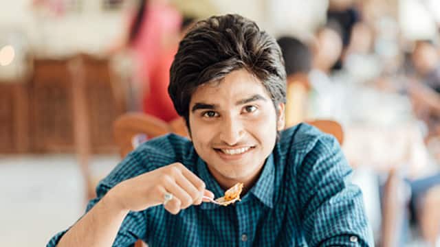 man smiling holding a spoonful of food