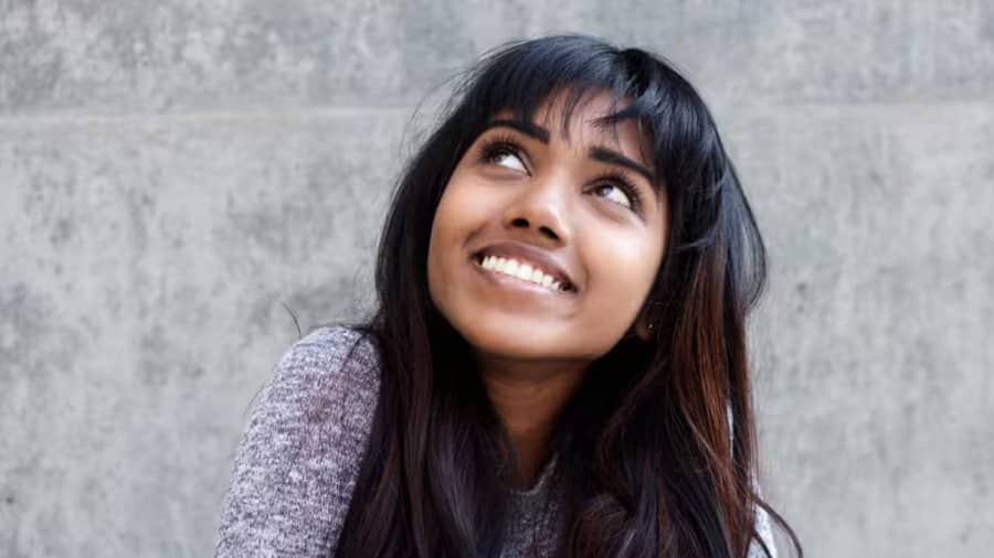 A young lady smiling confidently after getting treatment for a black stain on teeth