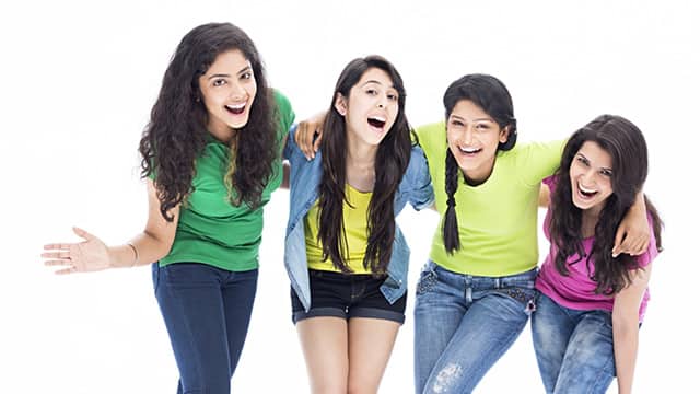 four woman laughing with their arms around each other