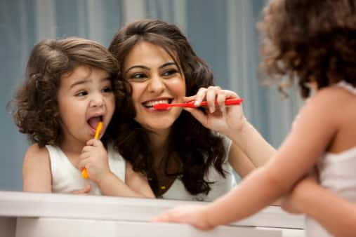 Mom teaching her daughter brush teeth 