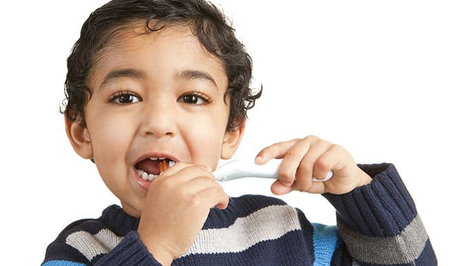 Toddler brushing his teeth with personalized toothbrush