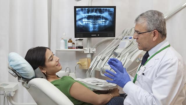 a dentist talking a a patient sitting on the dental chair