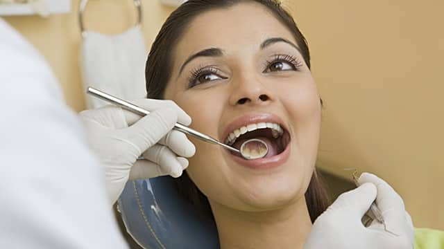 dentist inspecting patient mouth with a dental mirror