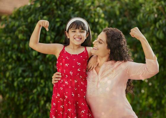 mother smiling at her daughter, while the daughter holds a bag full of apples