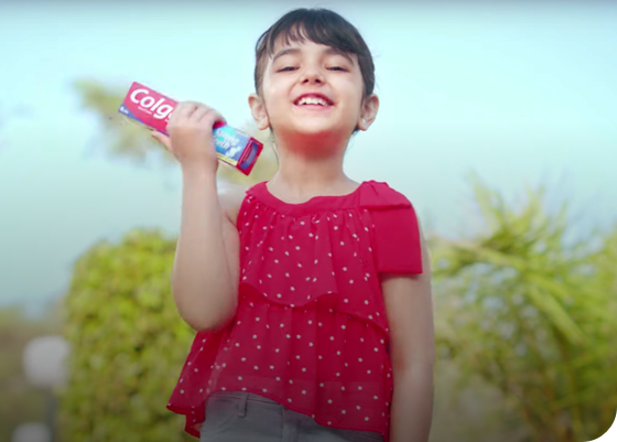 young girl smiling holding Colgate toothpaste