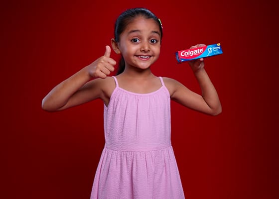 young girl smiling holding Colgate toothpaste