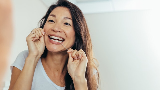 girl using dental floss on teeth