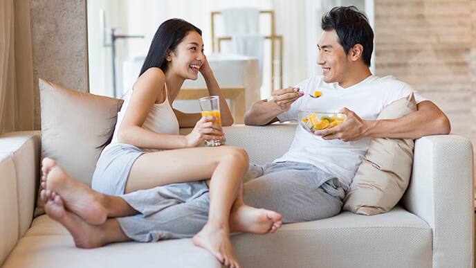 Asian couple having breakfast on couch