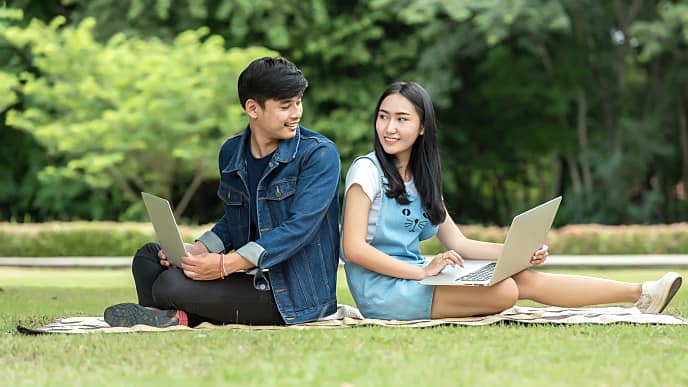 students using laptop in a park