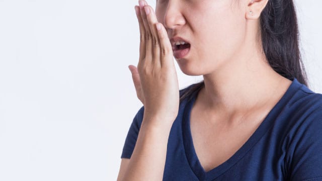 Lady checking her breath, showing discomfort due to bad breath