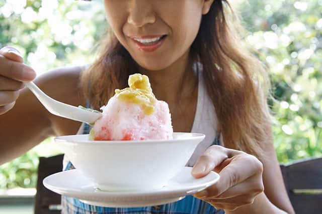 woman smiling while eating a shave ice