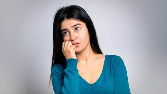 woman frowning with her right hand on her cheek