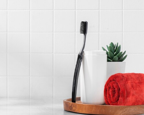 Colgate SlimSoft Charcoal Toothbrush leaning against a cup 