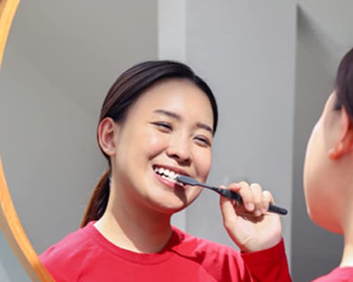 Asian woman brushing her teeth with Colgate SlimSoft Charcoal Toothbrush 