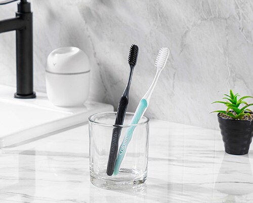 Two Colgate SlimSoft toothbrushes in a cup