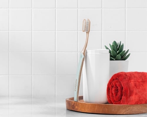 Colgate SlimSoft Gold Toothbrush leaning against a cup 