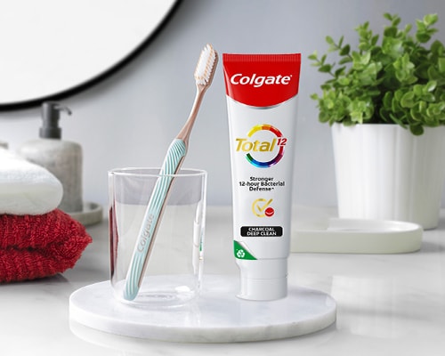 Colgate SlimSoft Gold Toothbrush leaning against Colgate Total Plaque Release Toothpaste