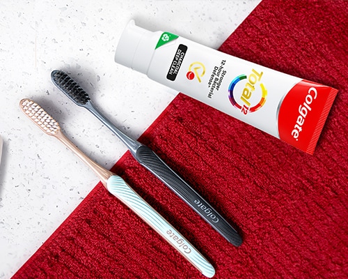 Two Colgate SlimSoft toothbrushes next to Colgate Total Plaque Release Toothpaste 