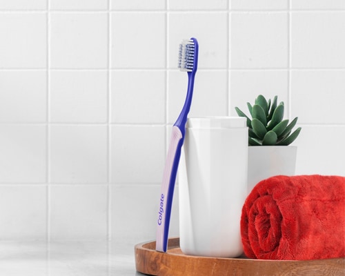 Colgate SlimSoft Ortho Toothbrush leaning against a cup 