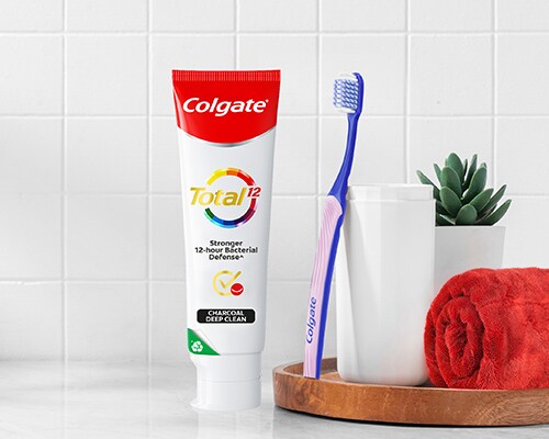 Colgate SlimSoft Ortho Toothbrush leaning against Colgate Total Plaque Release Toothpaste