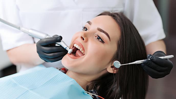 dentist doing a teeth cleaning to her patient