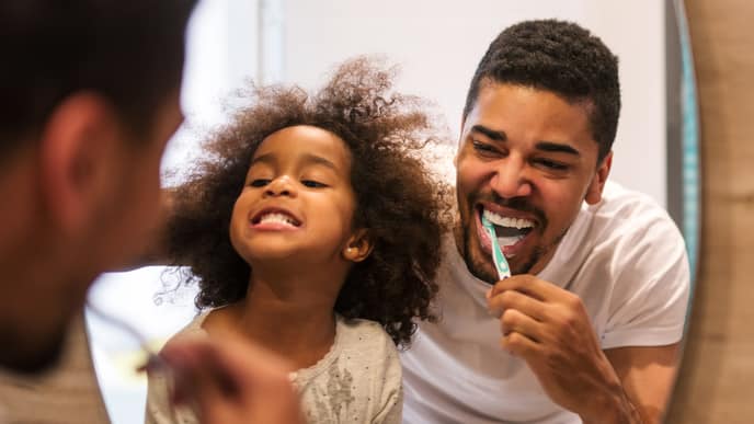 Father and daughter are brushing their teeth over the sink