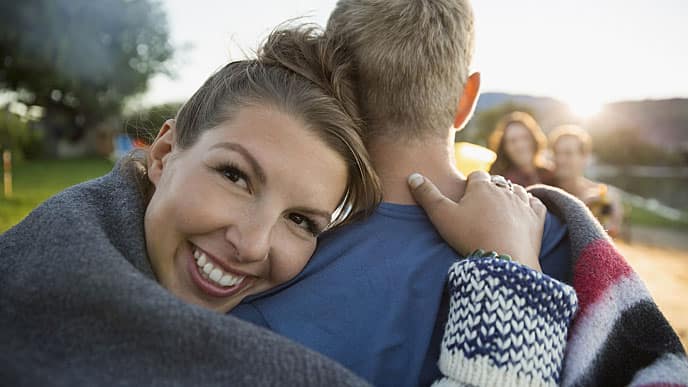 A woman smiling brightly outdoor next to a man