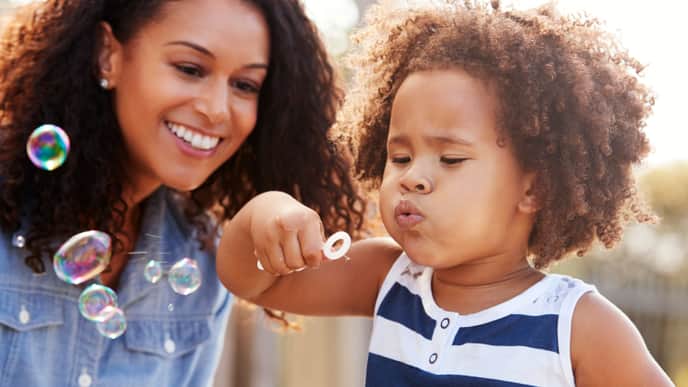 Baby blowing bubbles with mother