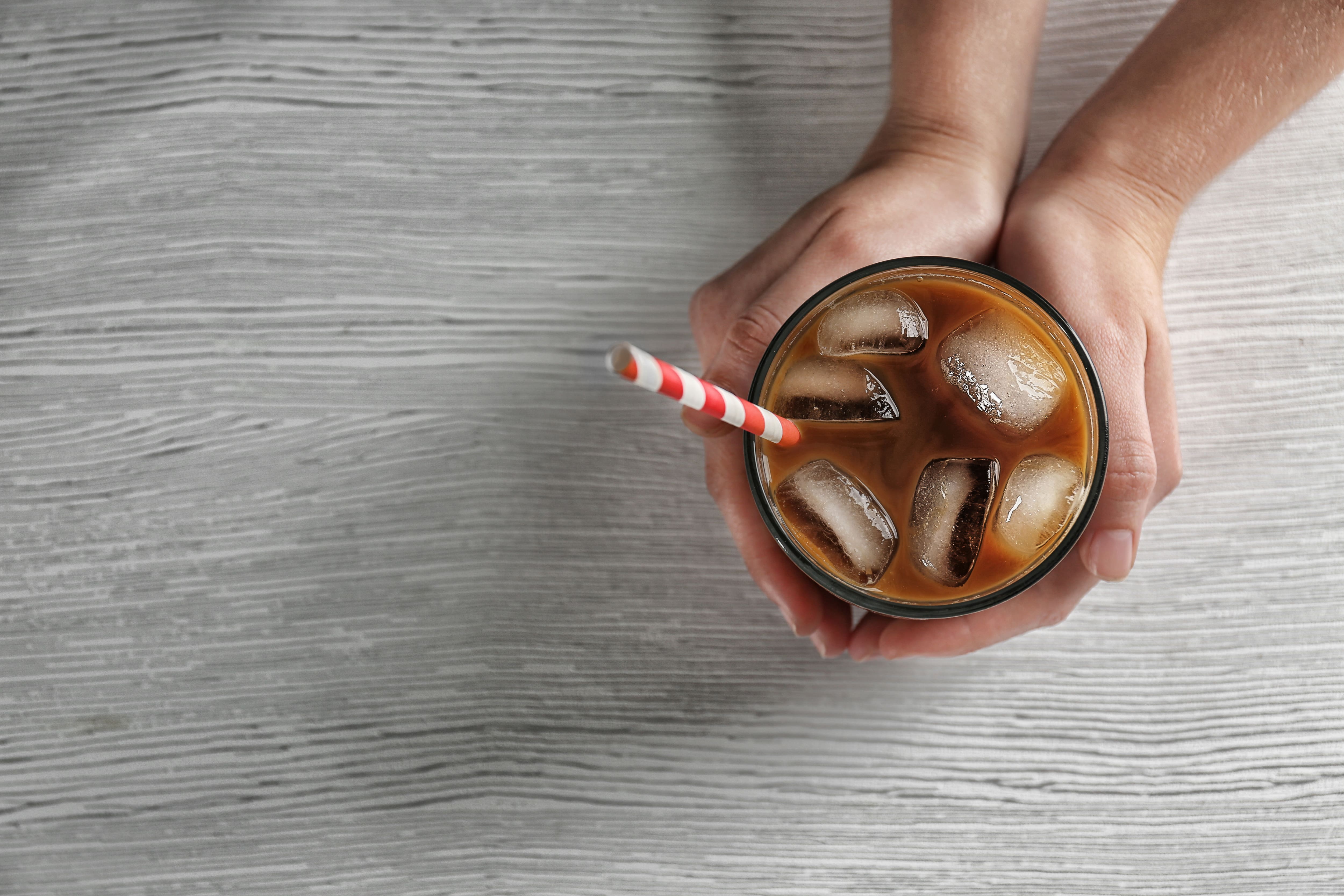 A close up of woman holding an iced coffee