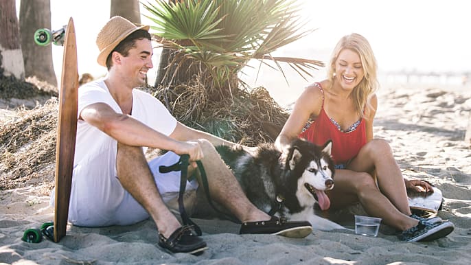 young couple relaxing on a beach with their dog