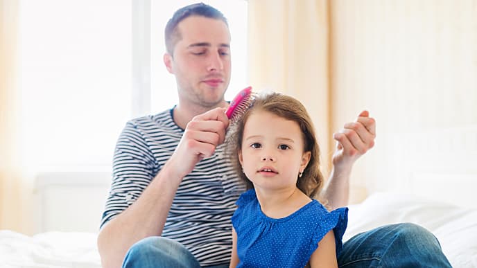 Father combing his daughter’s hair in the morning