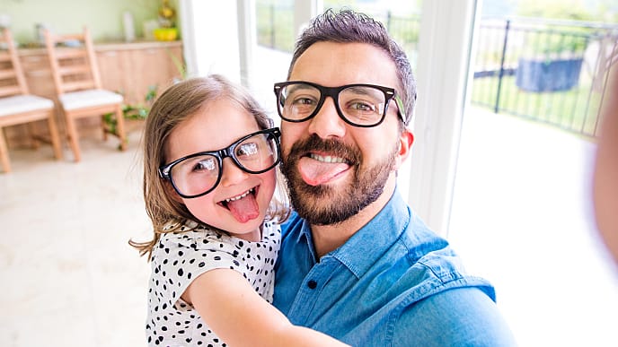 Papá e hija sonriendo y sacando la lengua