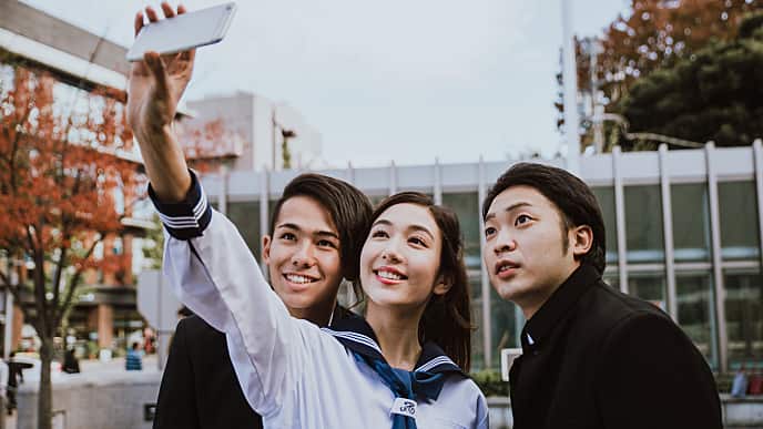 a woman smiling holding her phone taking a group photo with two men smiling