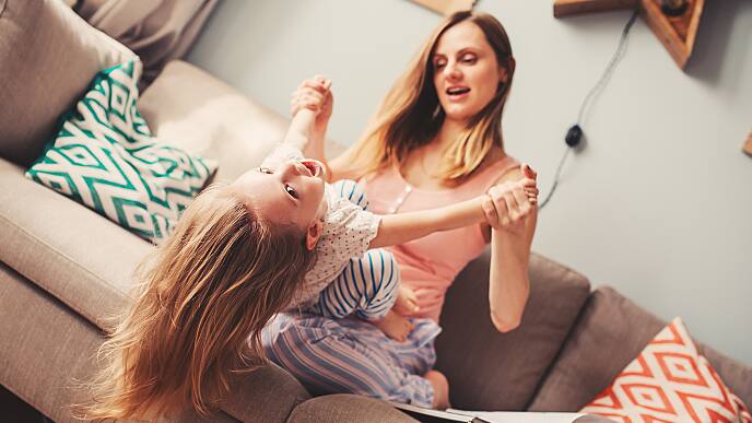 woman and daughter playing on the sofa