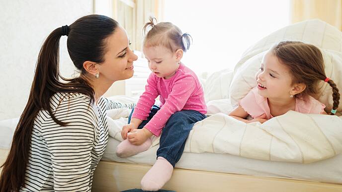 Dos hermanas dentando y su mamá riendo