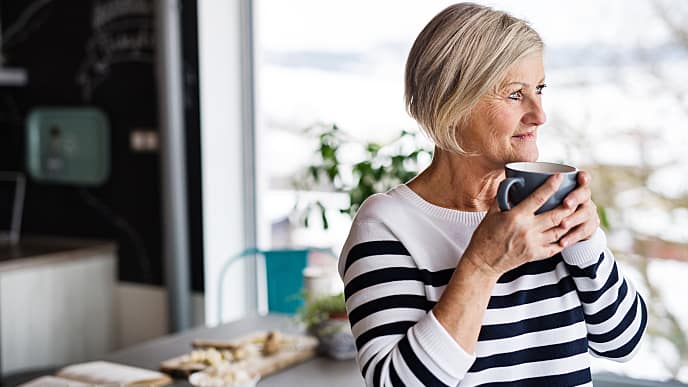 an old woman is drinking tea to cope with her abscessed teeth at home