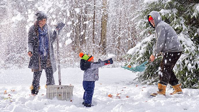 Parents and kid are shoveling snow in winter outdoor