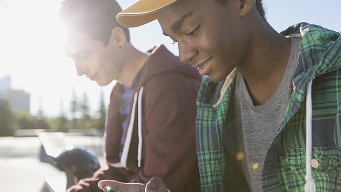 Two boys sitting outside with their mobile phones