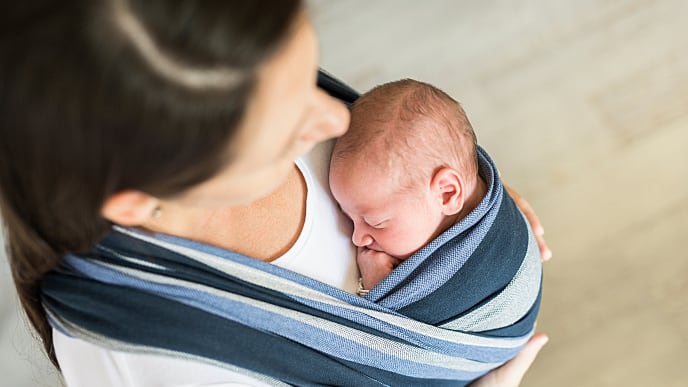 mother holding her baby on a baby sside sling