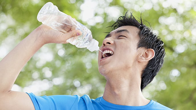young man drinking water in park