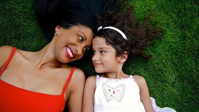 Mother and daughter laying on the grass