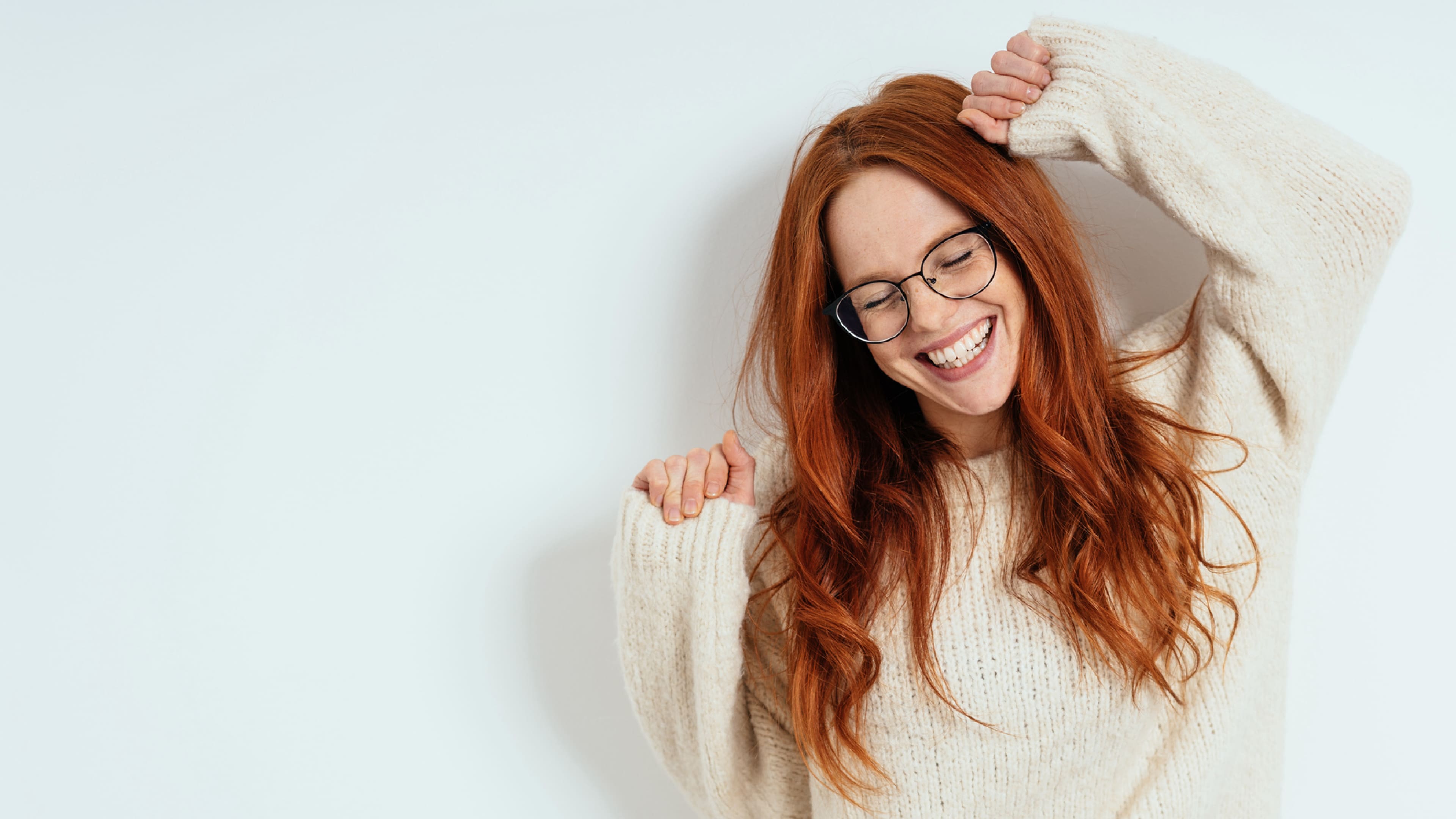 woman with glasses smiling brightly with her hands up