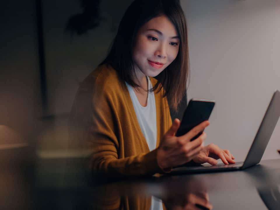 mujer sonriendo mientras usa su celular mujer sonriendo mientras usa su celular
